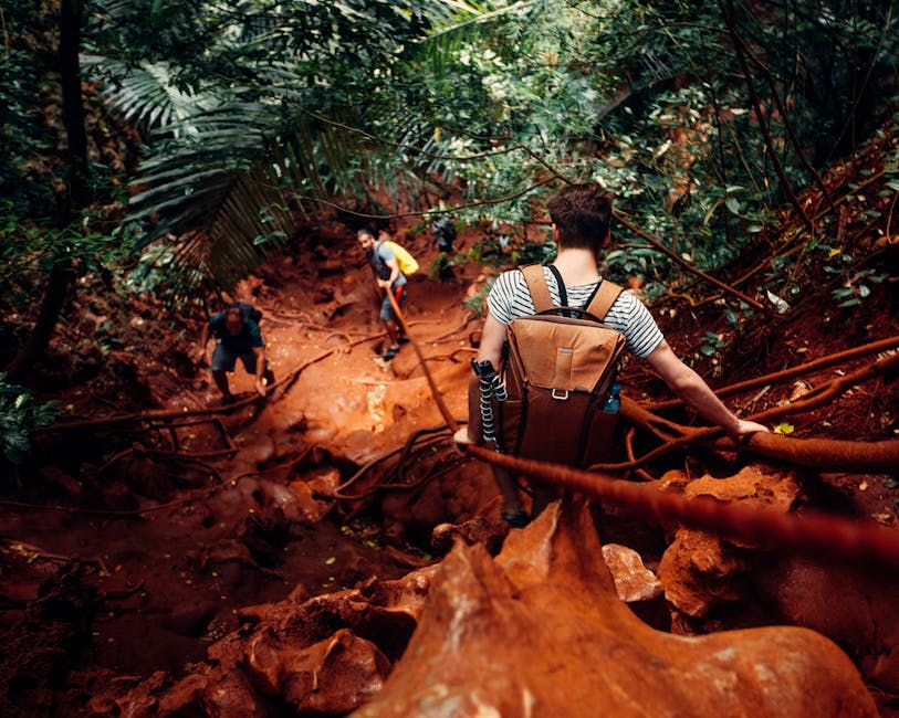 Hikers navigating a muddy trail during the rainy season on the Lost City trek, wearing raincoats and using hiking poles